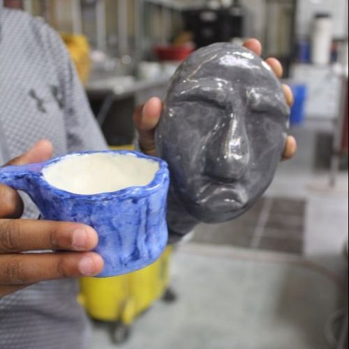 Erick Dawkins shows off two of his pieces from his first ceramics course.